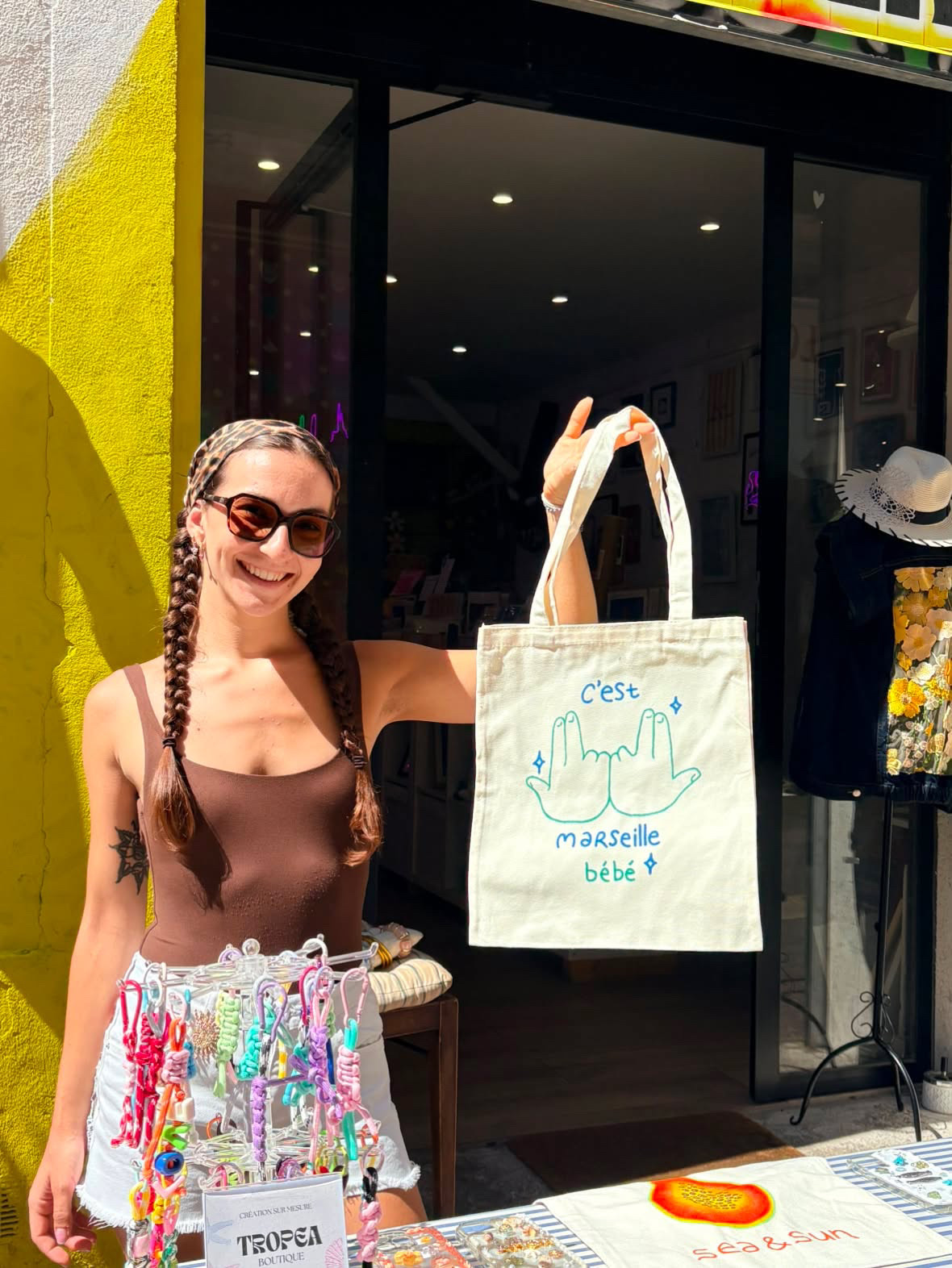 Maria Yanez, créatrice de Tropea Boutique, avec un tote bag peint à la main devant sa boutique à Marseille